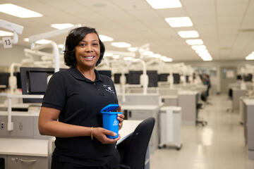Adrianne Snipes holding a small recycling bin inside a clinical lab